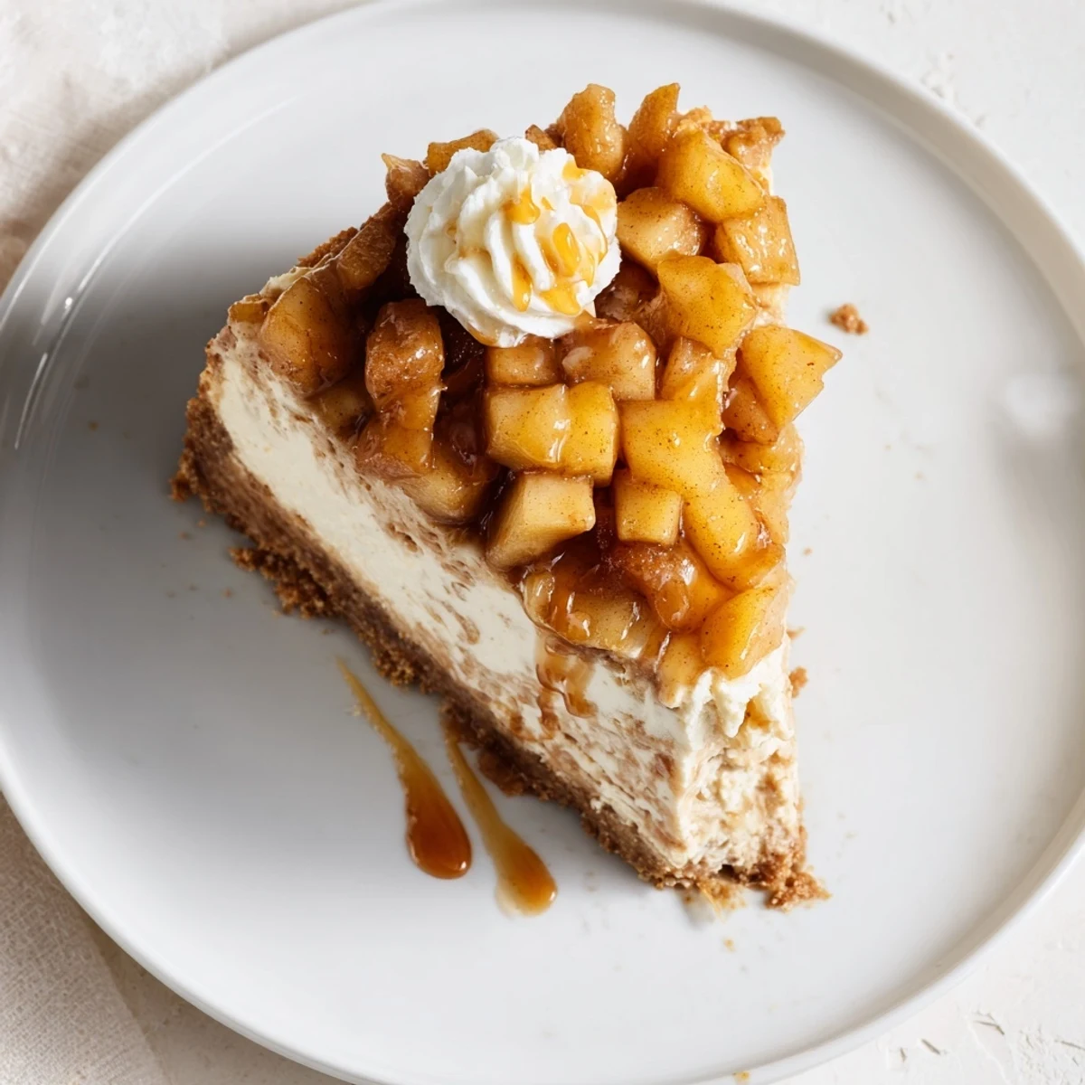 Delicious cinnamon apple bourbon cheesecake garnished with spiced apples and whipped cream.  