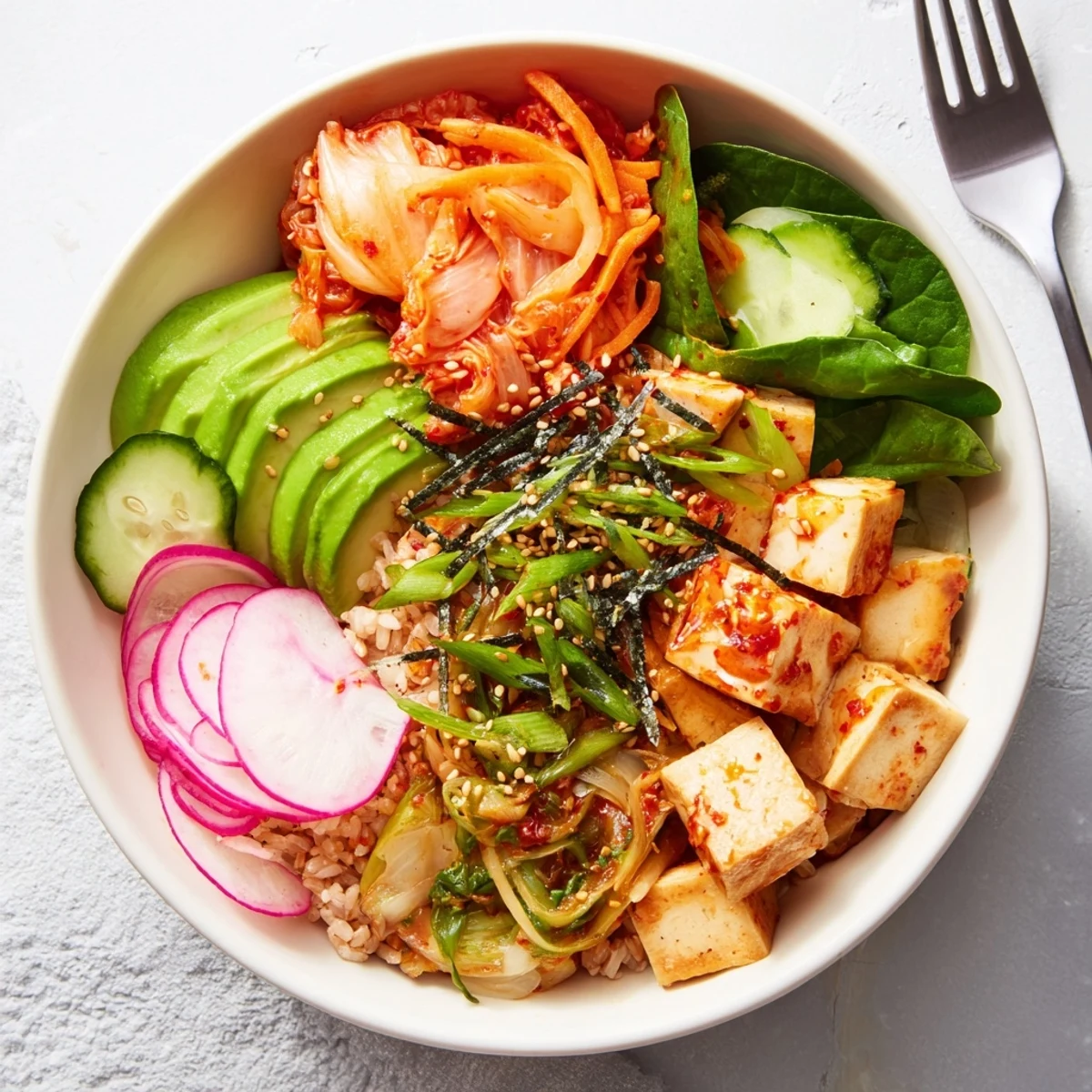 Deliciously vibrant fermented vegetable bowl topped with sliced avocado and tangy dressing.  
