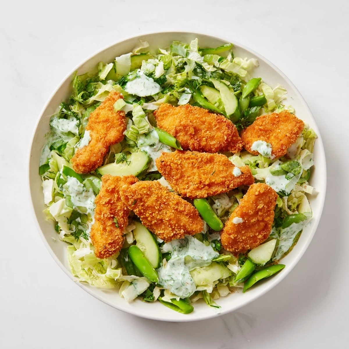 Freshly air-fried chicken nuggets sit atop a colorful bed of cabbage in this Green Goddess recipe.