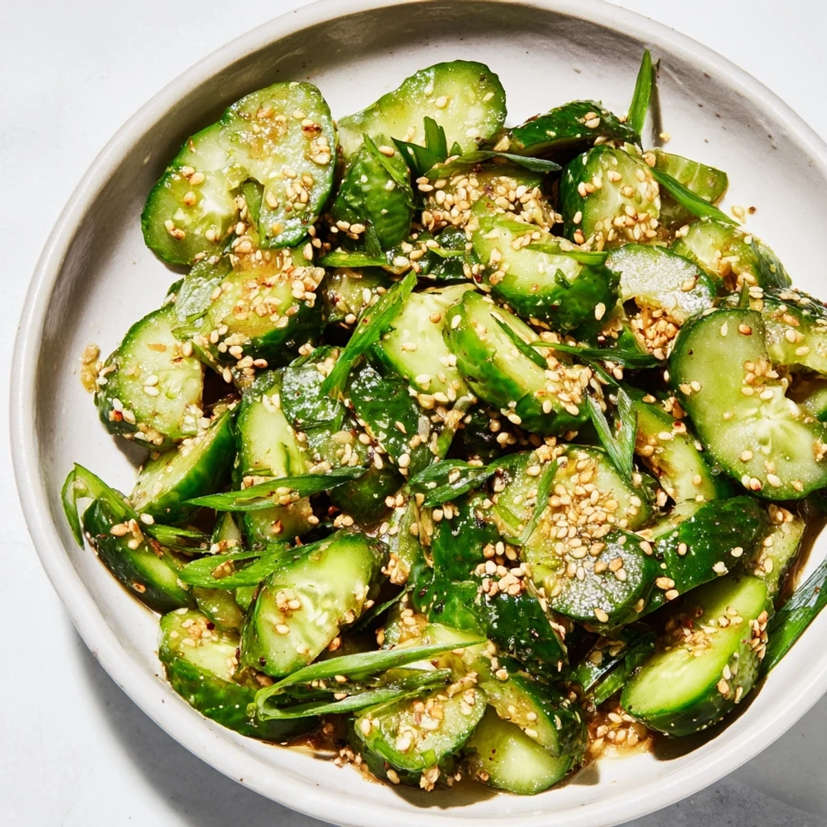 Bright green bite-sized pieces of Cucumber Shaker, boasting savory flavors and a drizzle of oil.