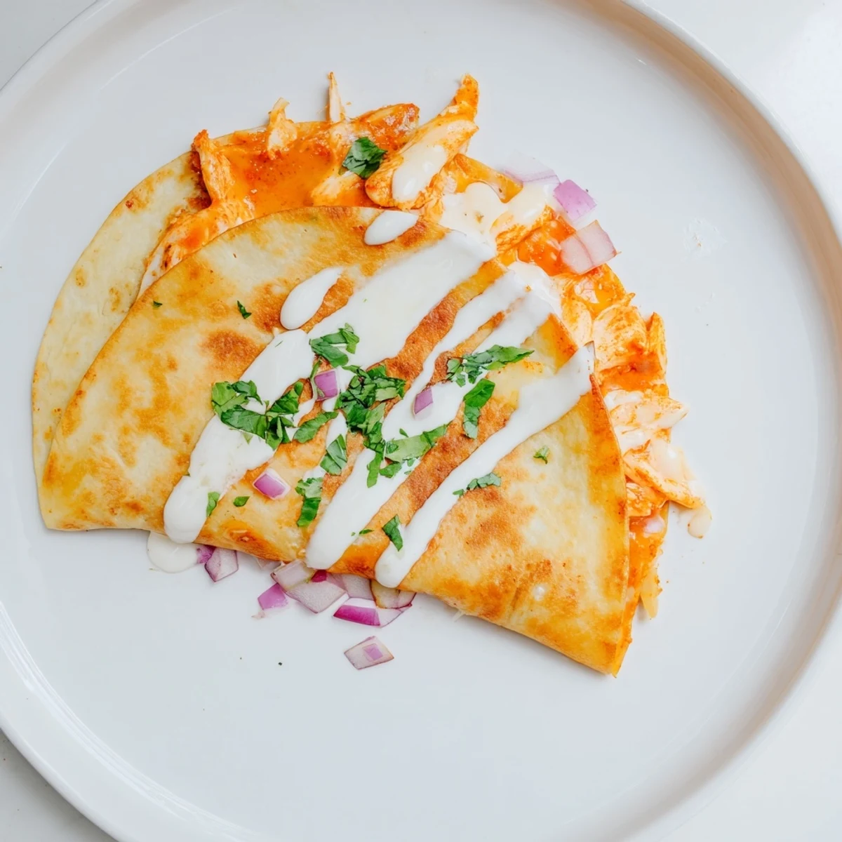 Close-up of a spicy Buffalo Chicken Quesadilla showing shredded chicken, cheese, and folded tortilla.