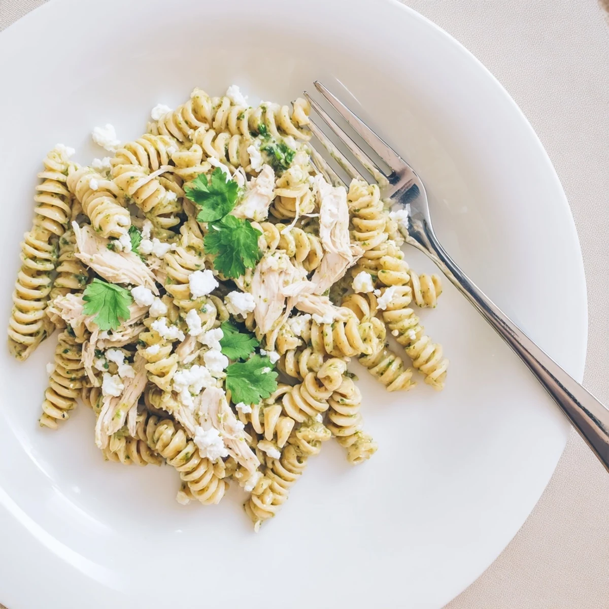 Creamy cilantro lime chicken pasta in a vibrant green sauce, topped with crumbled feta cheese and fresh lime wedges.