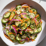 Refreshing cucumber salad remix featuring a tangy Asian-inspired dressing and colors.  