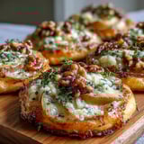 Freshly baked Pear, Gorgonzola, and Pickled Walnut Pizzettes with golden crusts and bubbling cheese are ready to serve.