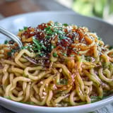 Glistening ramen noodles tossed in savory garlic butter sauce, sprinkled with sesame seeds and fresh scallions for bold flavor.