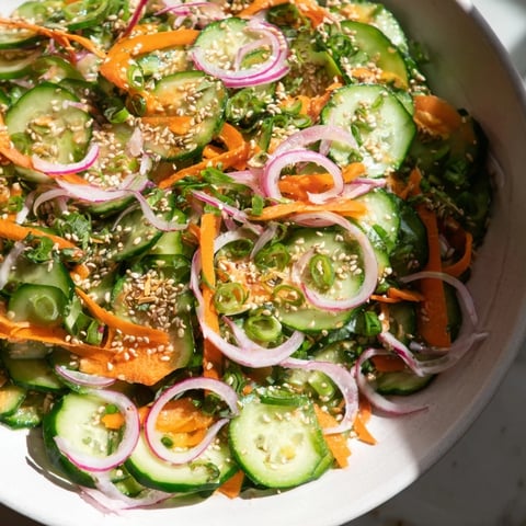 Vibrant cucumber salad remix topped with sesame seeds and fresh herbs for flavor.  