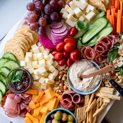 A vibrant girl dinner platter with assorted cheeses, fruits, and savory dips.