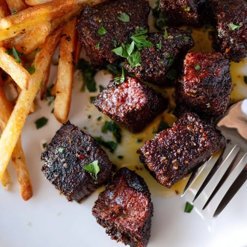 Succulent blackened Cajun steak bites paired with crispy golden fries on a plate.  
