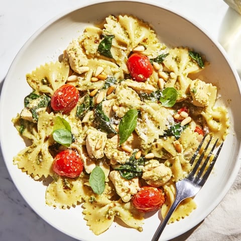 Pesto Chicken Bowtie Pasta topped with fresh basil and Parmesan, ready to serve.  
