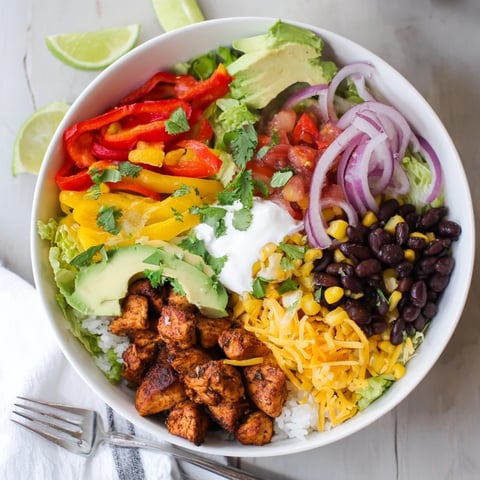 Juicy Sheet Pan Chicken Burrito Bowls topped with fresh vegetables and vibrant salsa.  