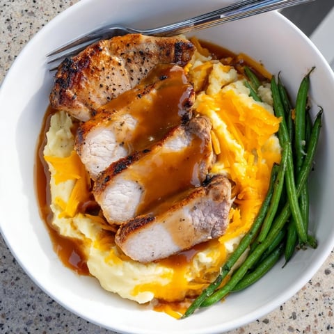 Juicy pork chops nestled on creamy cheddar mash, drizzled with savory gravy.  