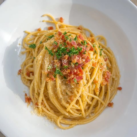 Creamy garlic butter pasta, glistening, finished with a generous, crispy bacon crumble; perfect for dinner.