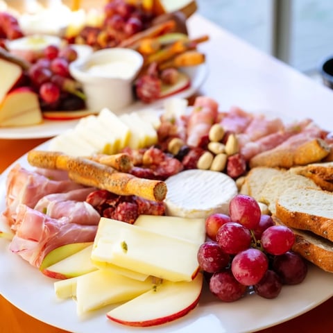A beautiful Cheval Heureux Snack Board overflowing with vibrant cheeses, meats, fresh fruits, and crackers.
