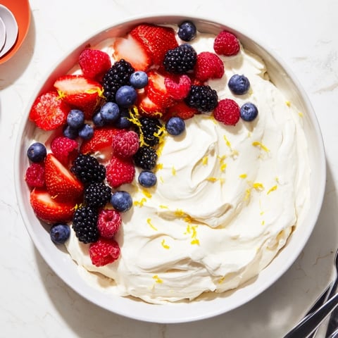 Fluffy cream cheese fruit dip with vibrant berries, a delightful, creamy dessert for sharing.