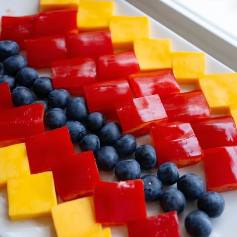 Vibrant Bauhaus Block appetizer showcasing red peppers, cheddar cheese, and juicy grapes artfully arranged.