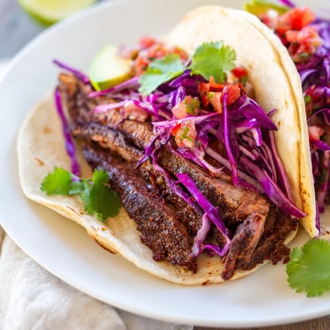 Coffee-Rubbed Steak Tacos, sliced steak glistening with spice, served in warm tortillas with vibrant toppings.