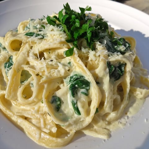 A steaming bowl of Creamy Spinach Fettuccine Alfredo, a delicious Italian-American main course.