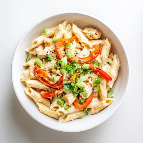 Steaming Sweet Chili Chicken Pasta with penne noodles tossed in a creamy, vibrant sauce with tender chicken and red bell pepper slices.  