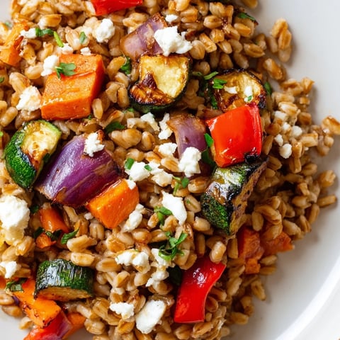 Golden-brown roasted vegetables and chewy farro glisten with balsamic glaze in a rustic serving bowl.