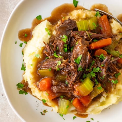 Hearty slow cooker pot roast with vibrant vegetables and buttery mashed potatoes.  