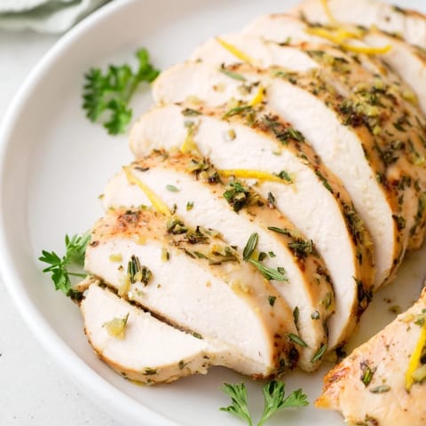 A close-up of delicious Greek Lemon Herb Chicken with bright herbs and lemon wedges, ready to enjoy.