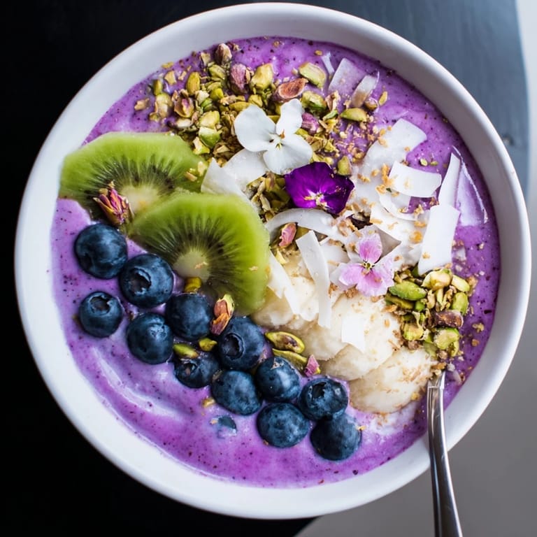 Healthy smoothie bowl bursting with flavors, topped with berries and edible flowers.