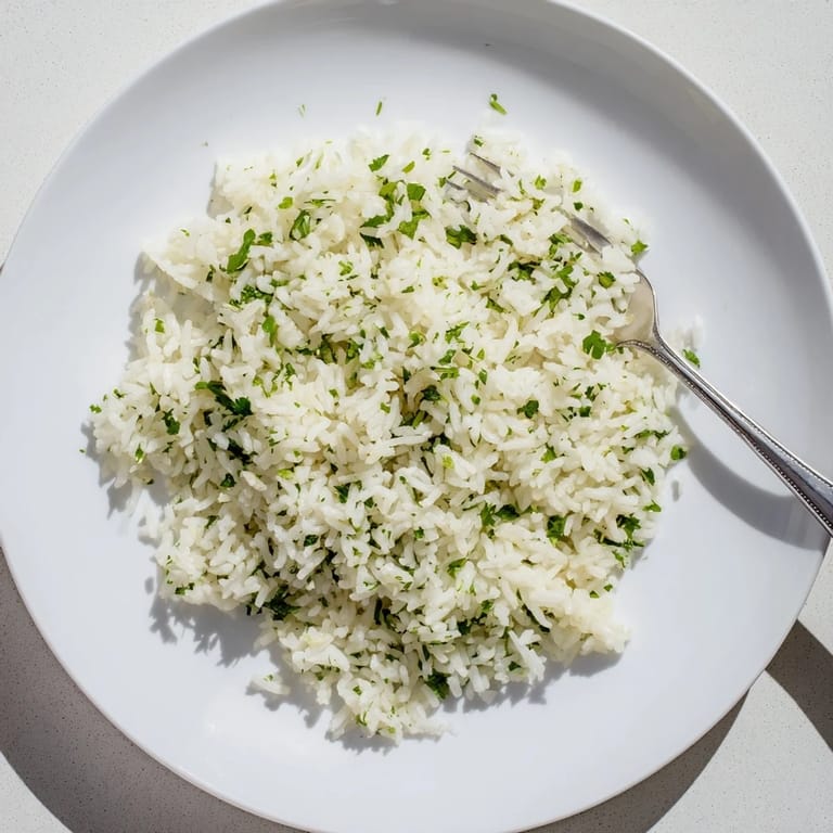 A close-up of fluffy Cilantro Lime Rice garnished with fresh herbs and citrus zest.  