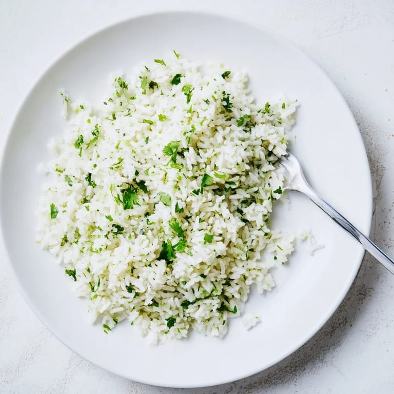 Steaming bowl of homemade Cilantro Lime Rice topped with chopped cilantro and lime wedges.